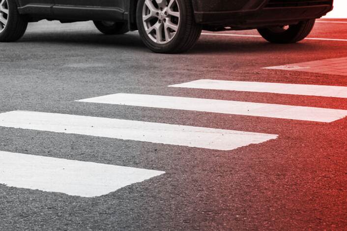 A car waits at a pedestrian crosswalk.